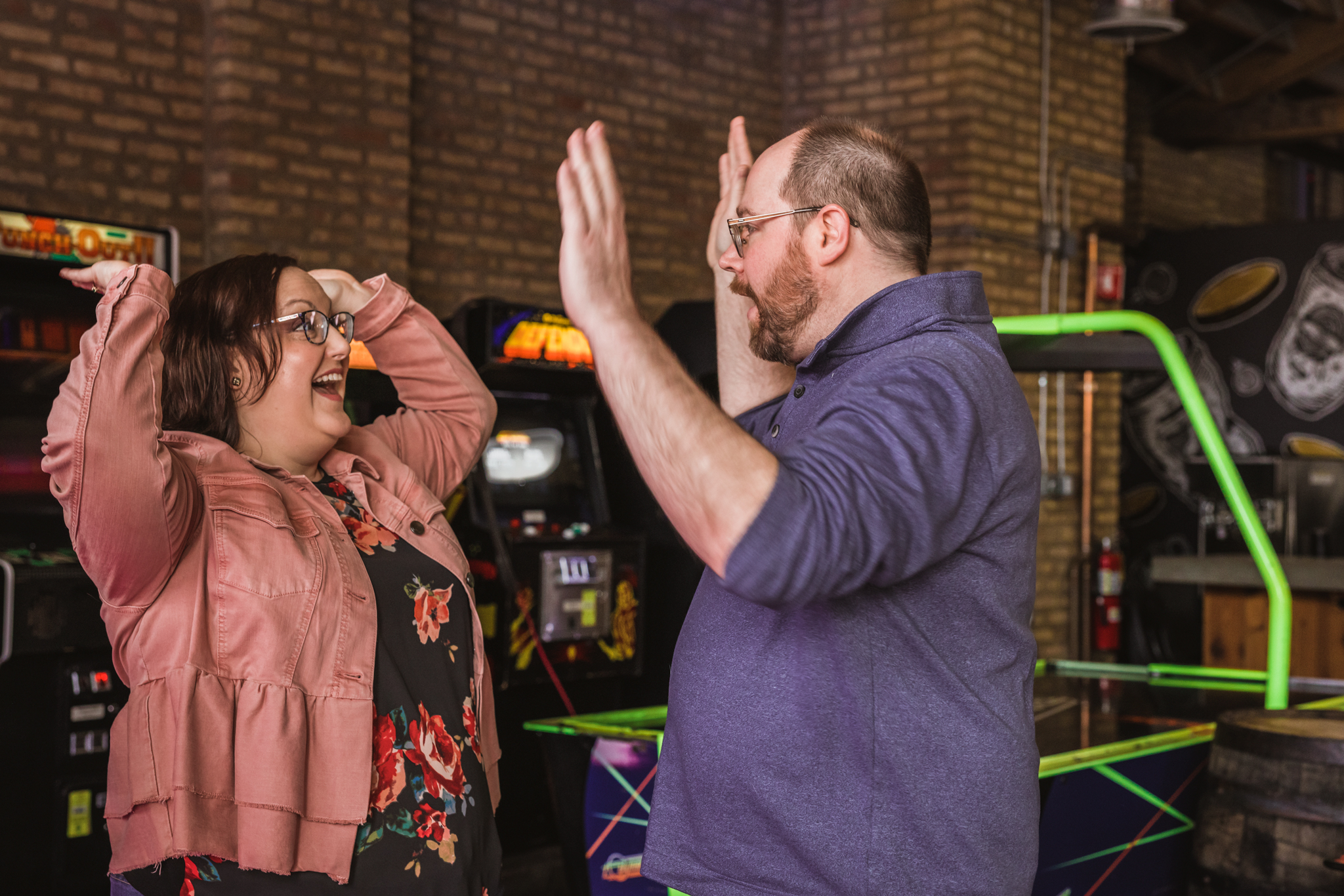 Couple slapping high five during their engagement session at the Emporium Logan Square in Chicago, IL