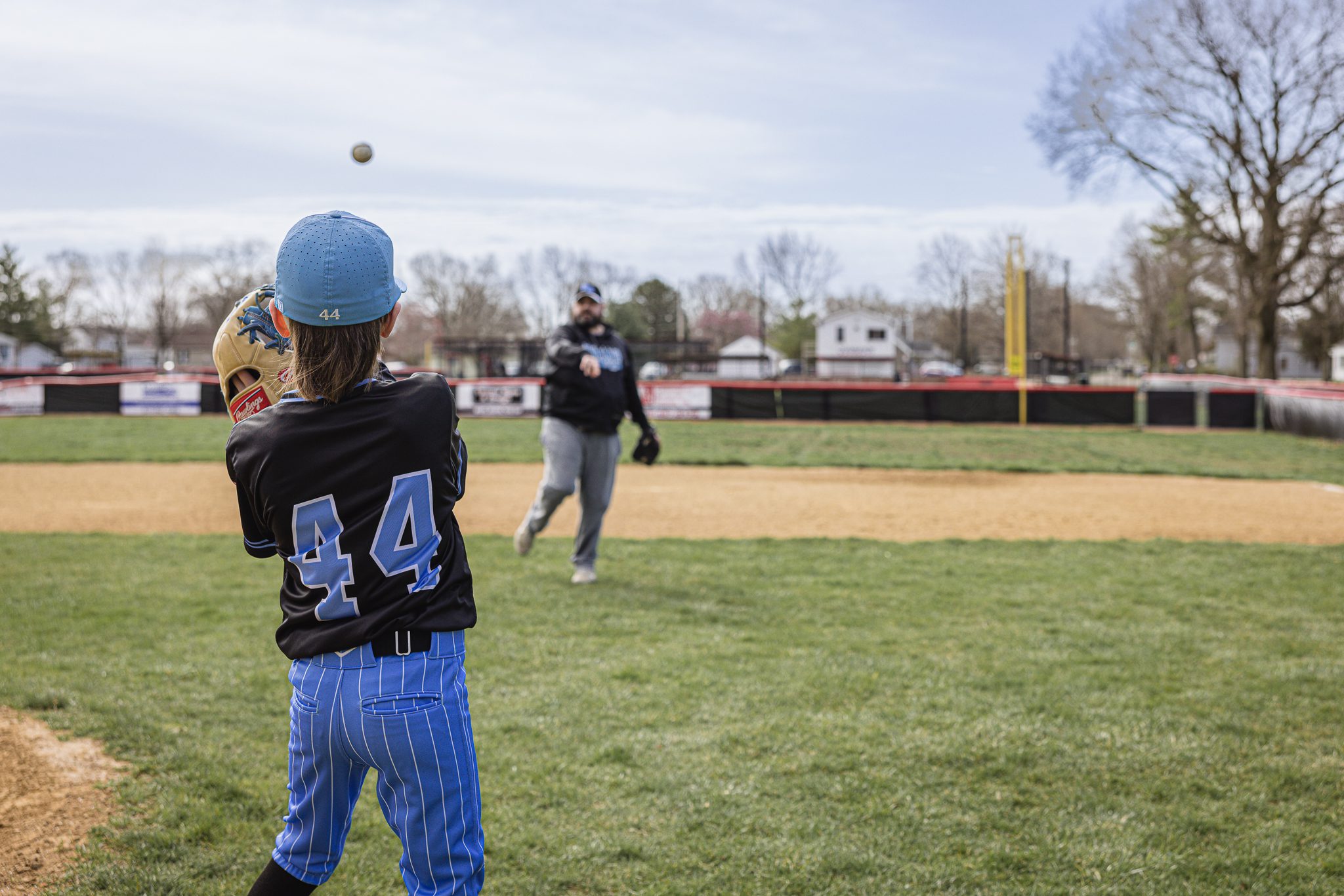 Boy in baseball uniform playing catch with his dad at Channahon Pony Baseball Fields in Channahon, IL