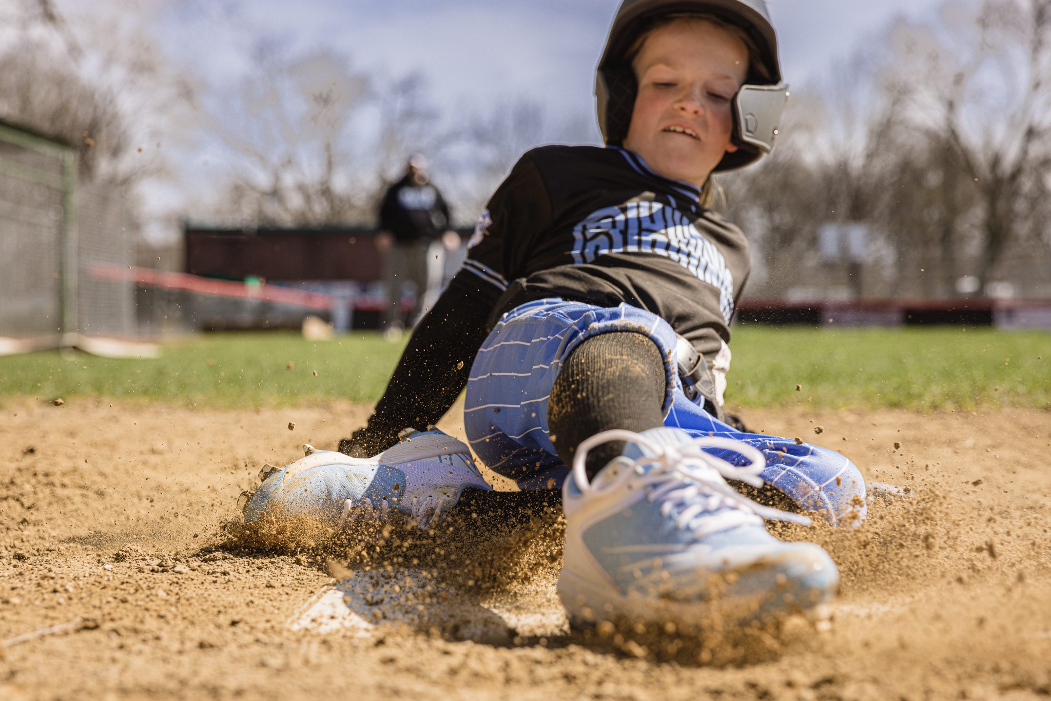 Boy in baseball uniform smiling after sliding into home plate at Channahon Pony Baseball Fields in Channahon, IL