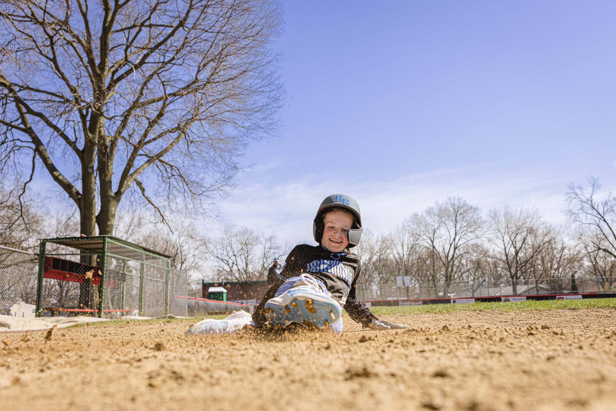 Boy in baseball uniform smiling after sliding into home plate at Channahon Pony Baseball Fields in Channahon, IL