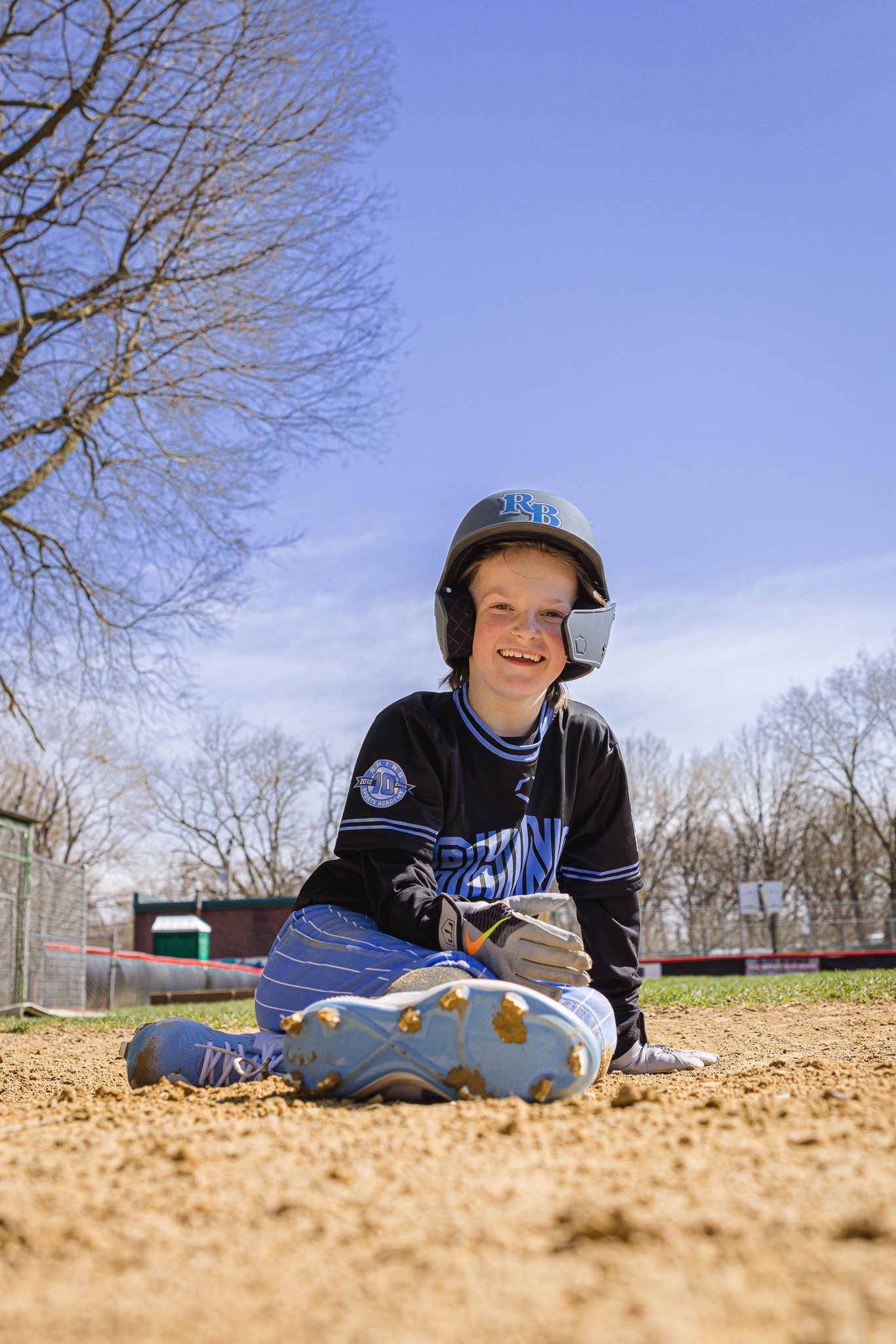 Boy in baseball uniform smiling after sliding into home plate at Channahon Pony Baseball Fields in Channahon, IL