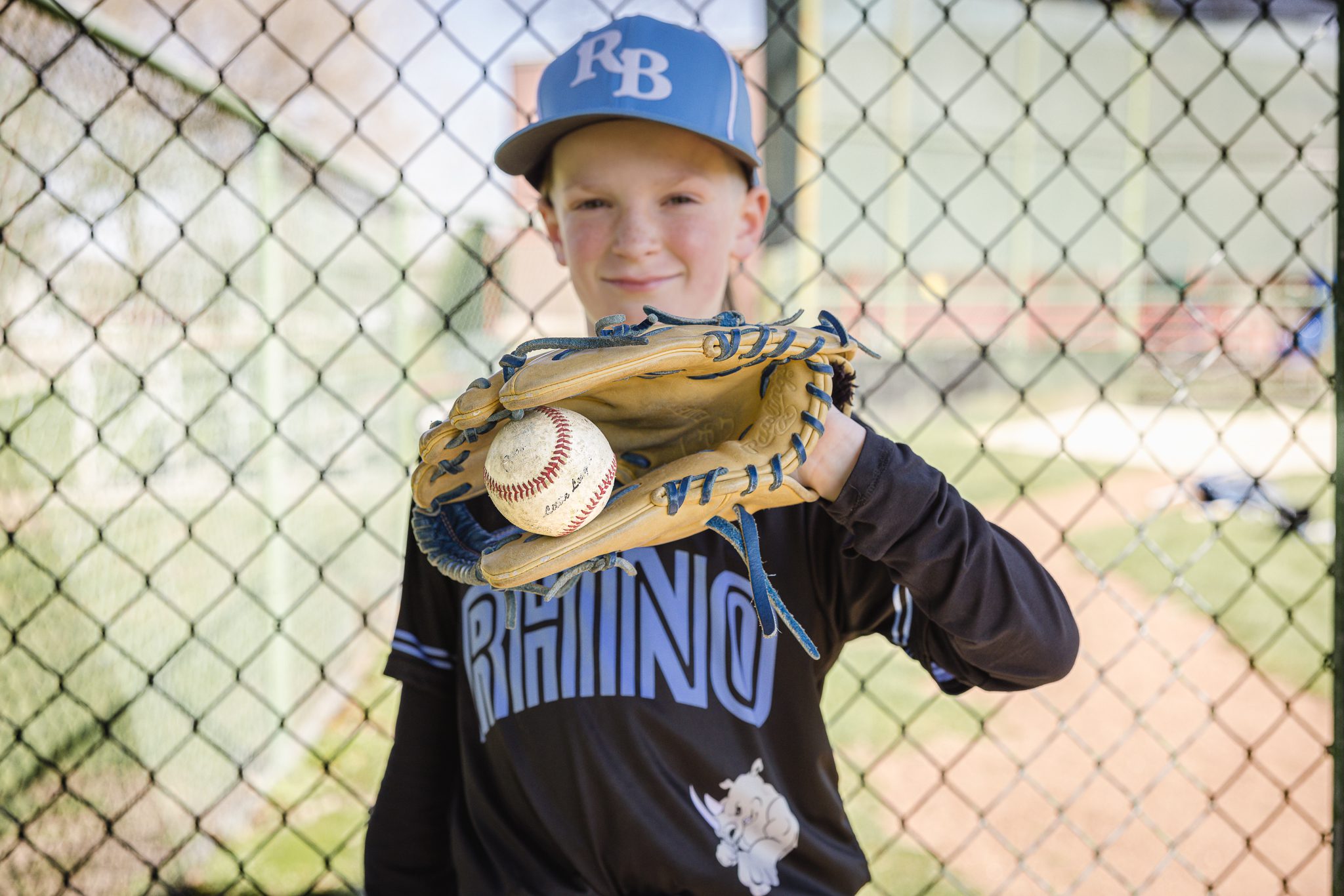 Boy in baseball uniform holding ball in his baseball glove at Channahon Pony Baseball Fields in Channahon, IL
