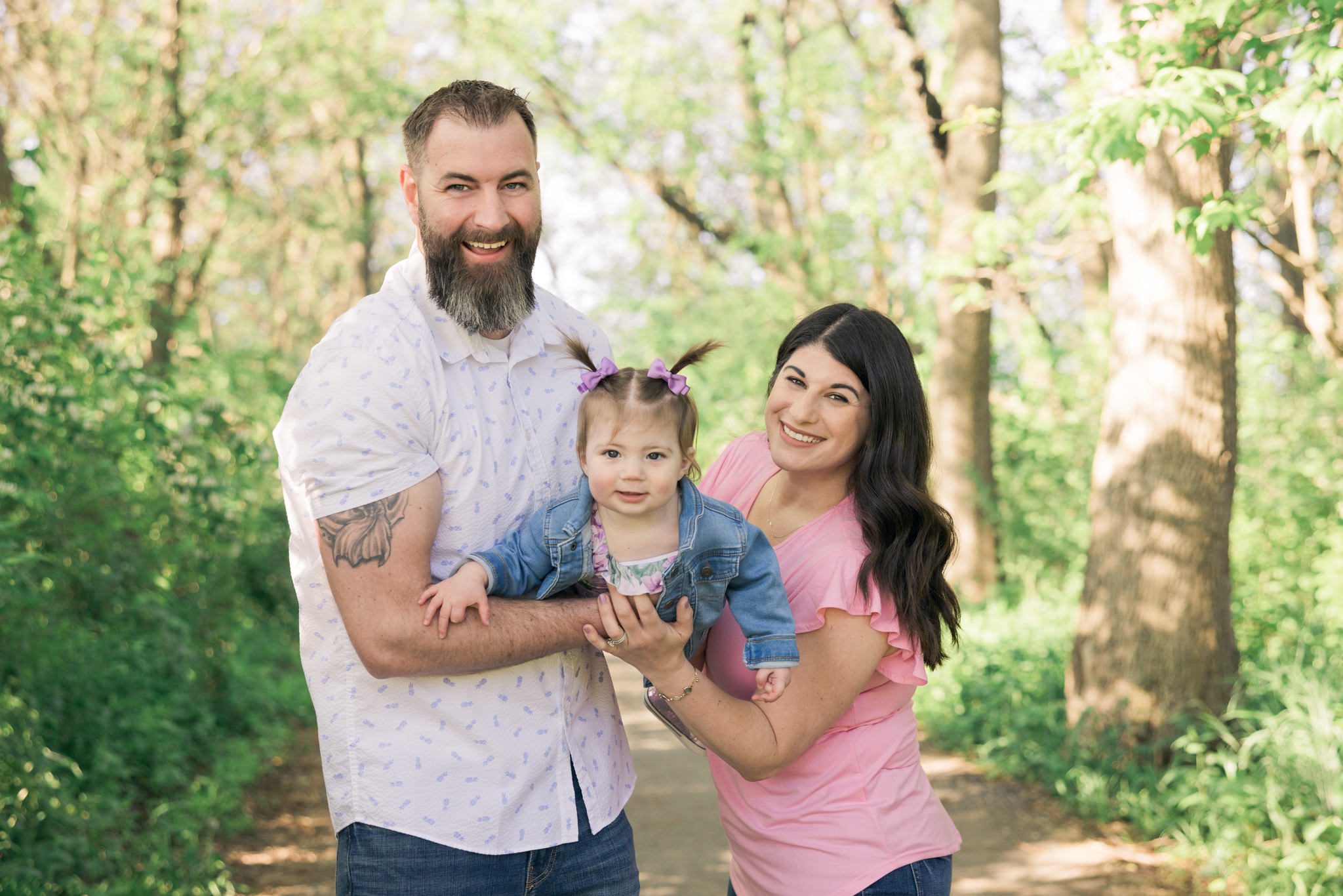 Mom and dad with their young daughter all smiling and looking at the camera. Taken during a family photography session in the western suburbs of Chicago.