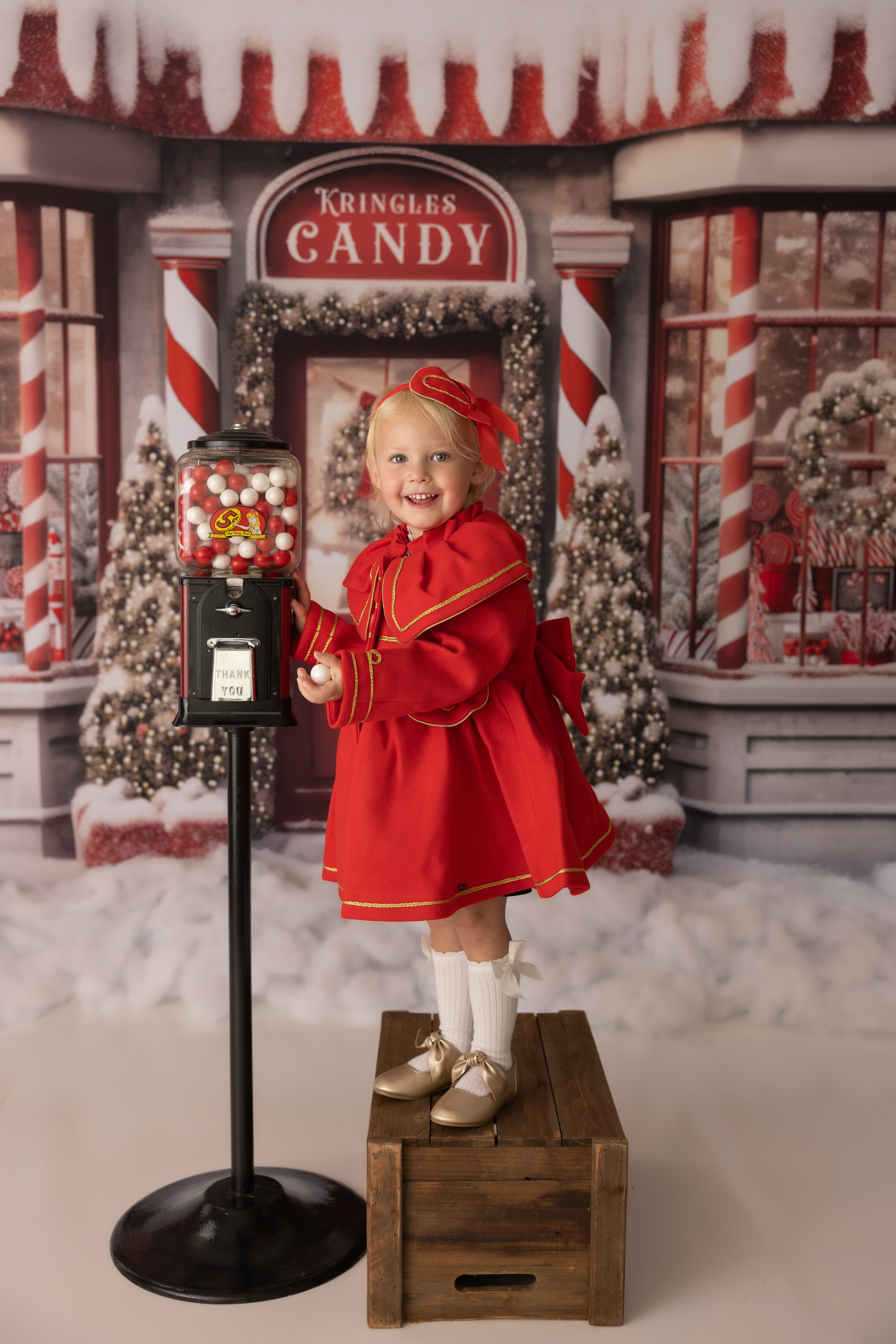 Young female standing on a crate and pulling a gum ball out of the gum ball machine. Photo taken during a holiday mini session in Warrenville, IL