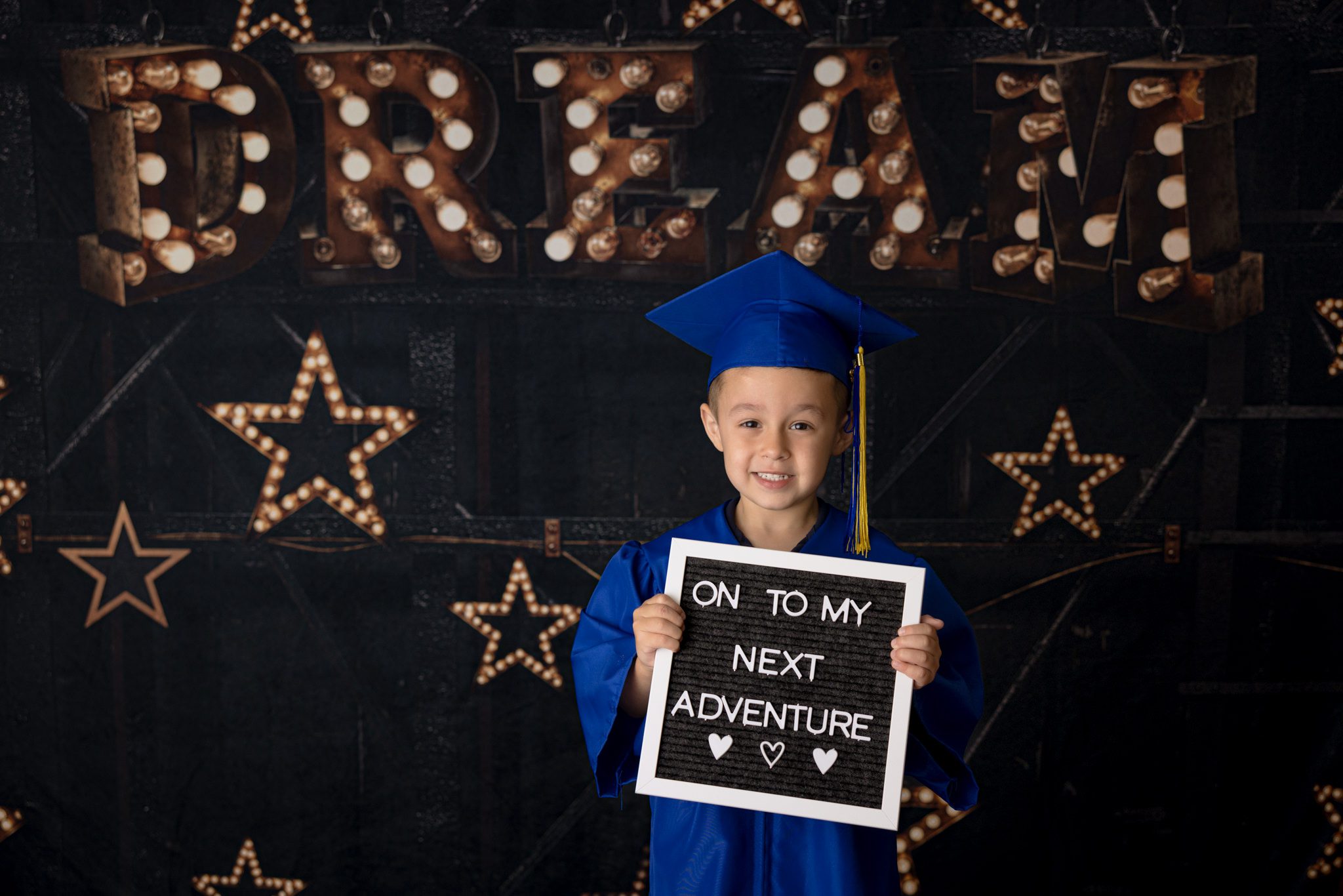 Young male in cap and gown holding a sign saying on to my next adventure. Photo taken during a cap and gown mini session in Warrenville, IL