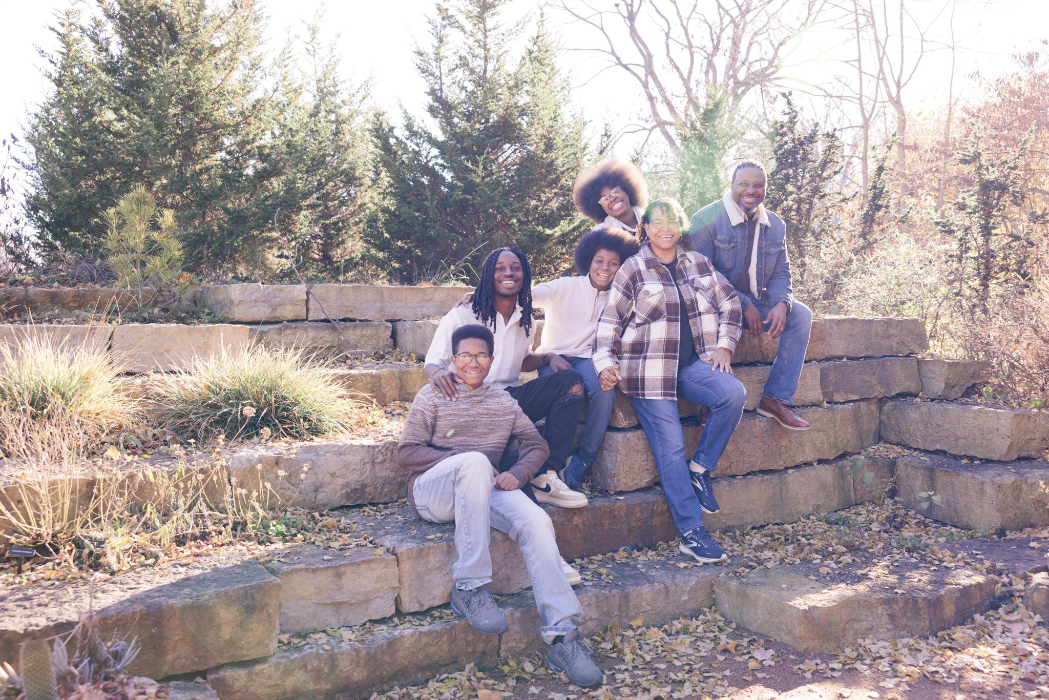 Family of 6 sitting on stack of rocks and smiling for the camera. Taken at Cantigny in Wheaton, IL