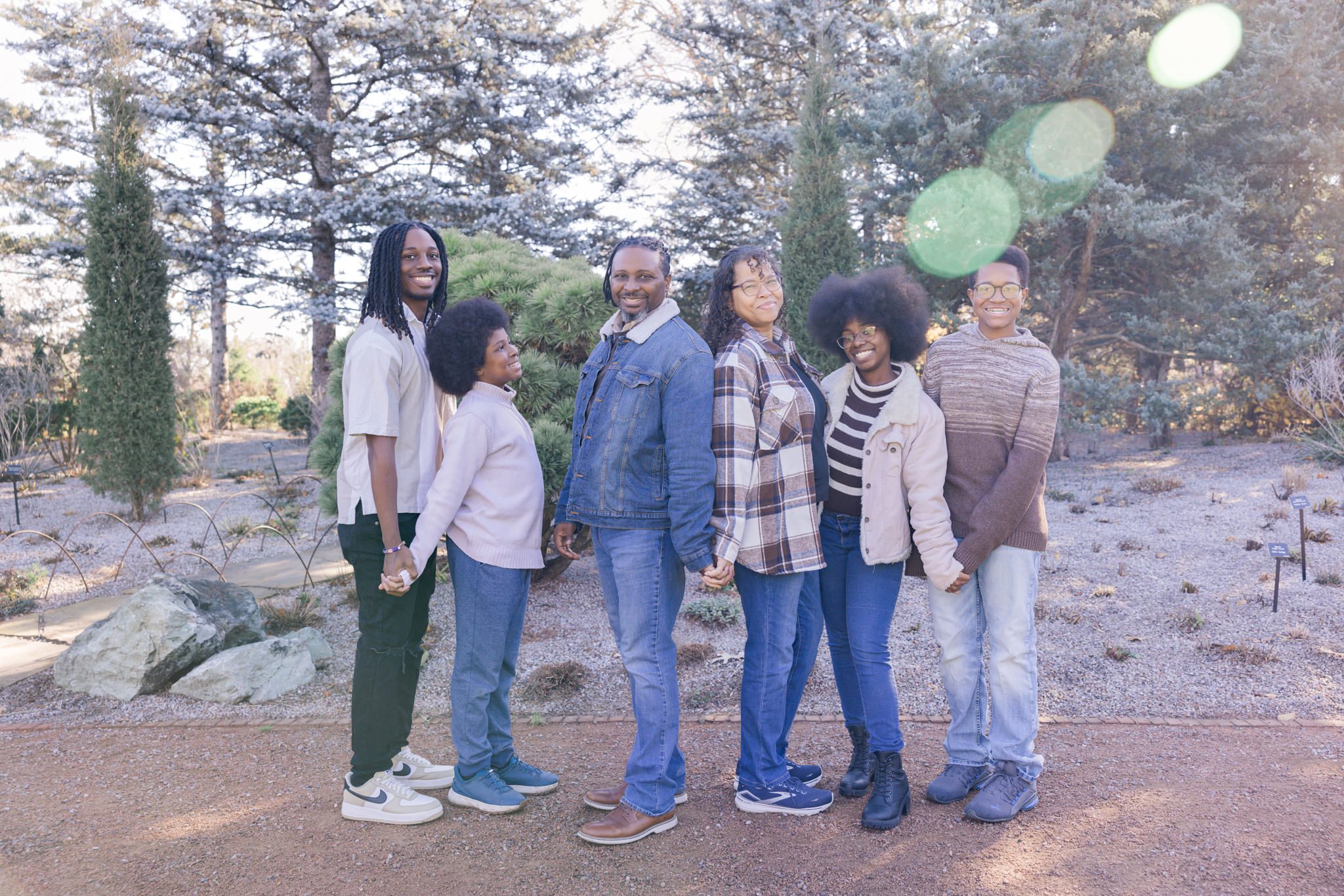 Mom and dad are standing back to back while their four grown children are smiling at the camera. Picture taken at Cantigny in Wheaton, IL