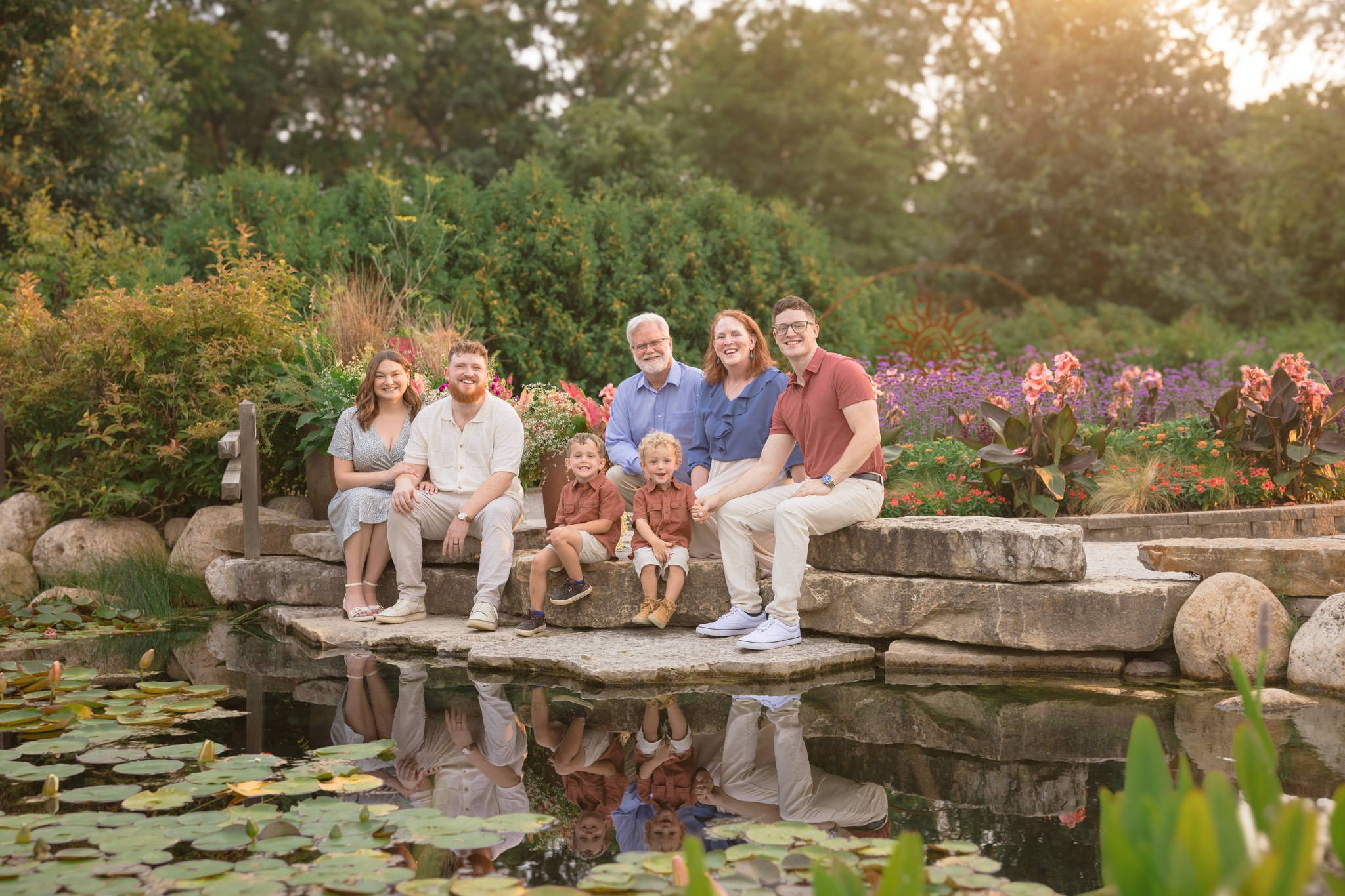 Extended family of seven sitting in front of a waterlily filled pond during a family photography session at Cantigny in Wheaton, IL