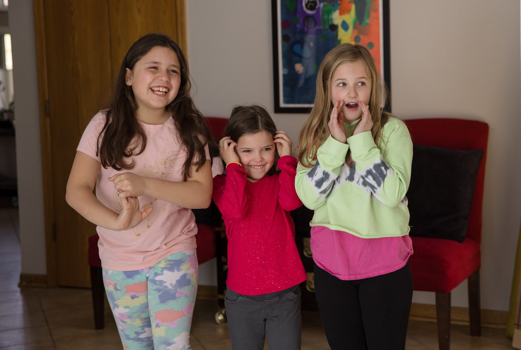 Three young girls looking off camera at the three dresses in which they will be wearing for their photography session in Warrenville, IL