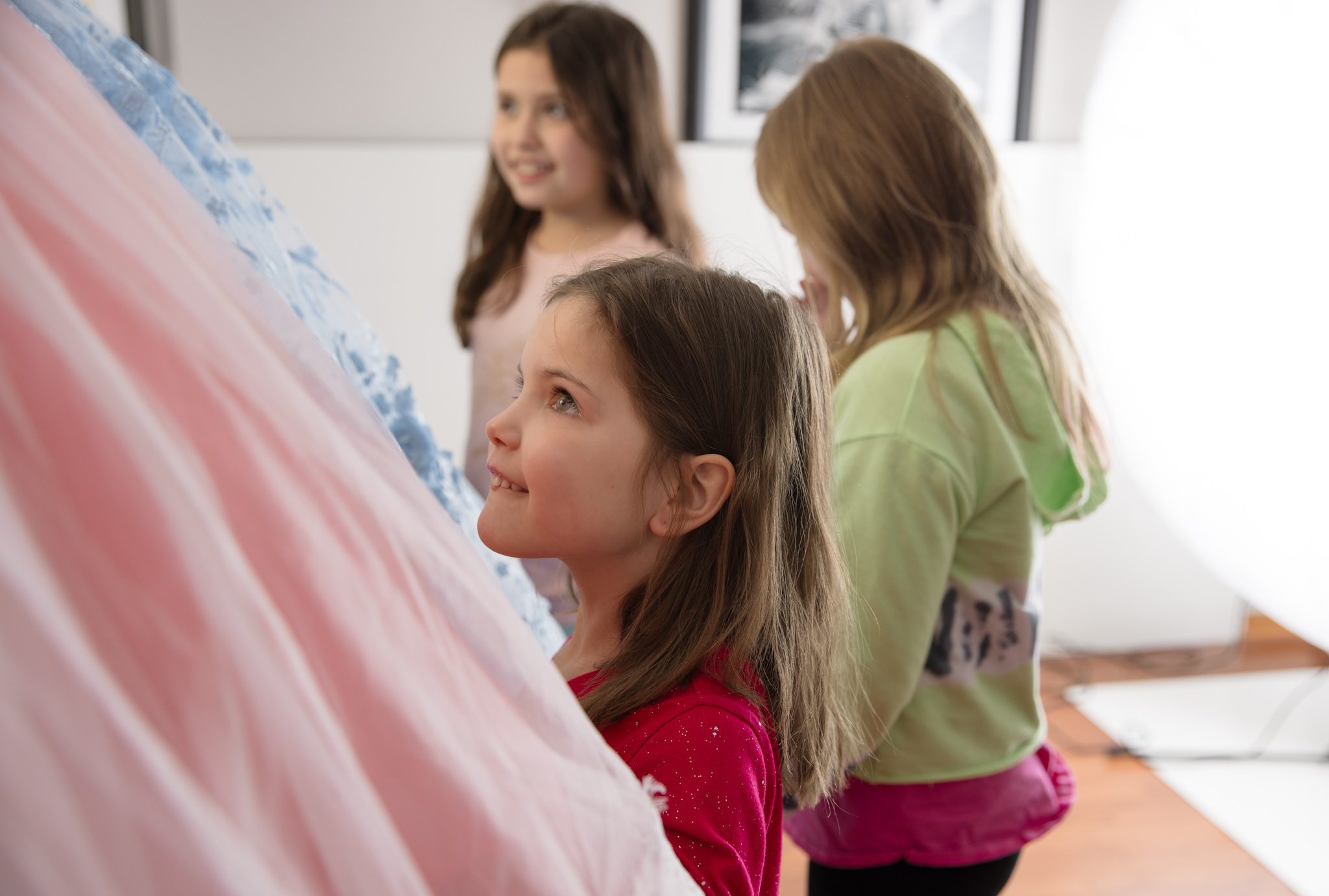 Three young girls looking at the three dresses in which they will be wearing for their photography session in Warrenville, IL