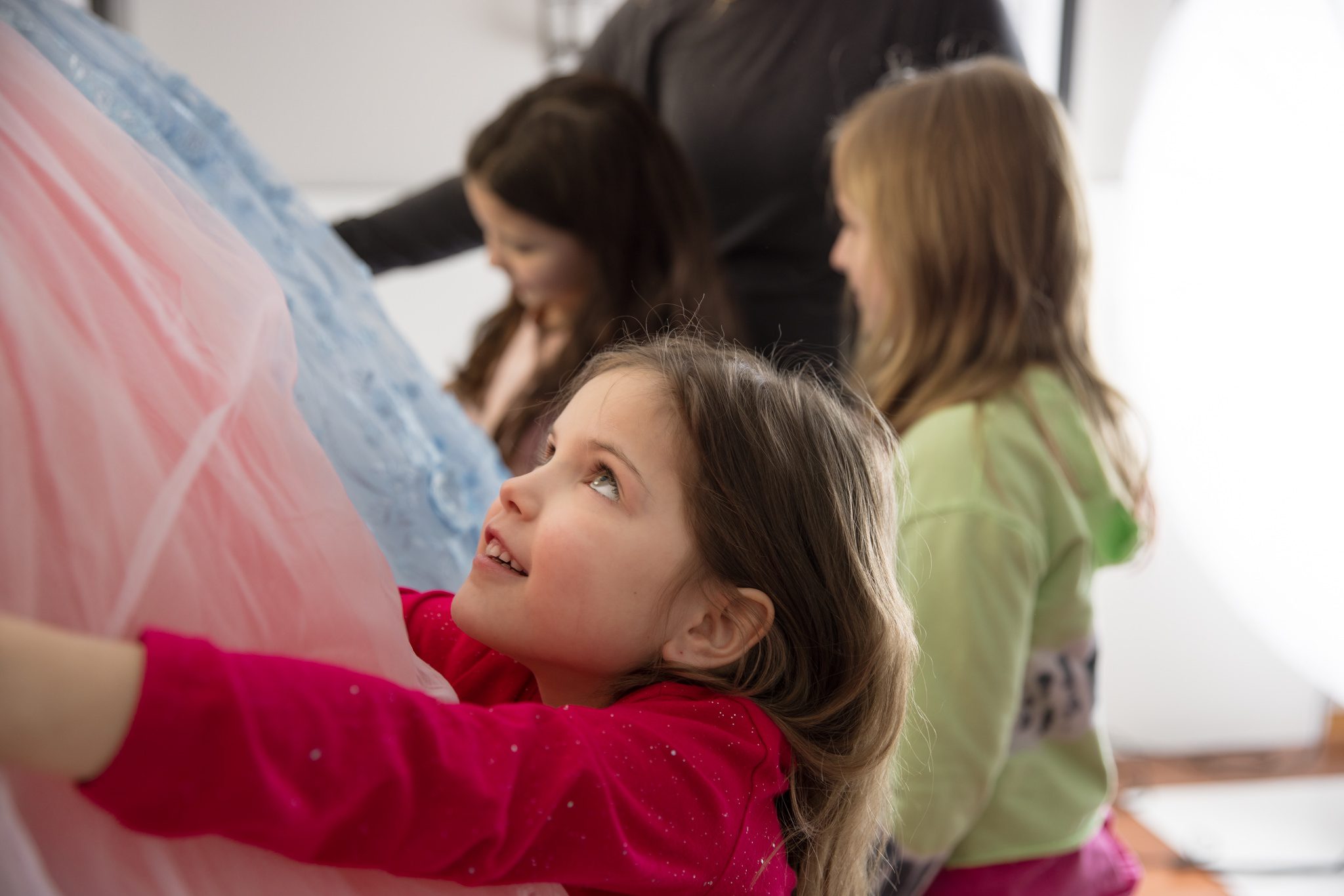 Three young girls looking at the three dresses in which they will be wearing for their photography session in Warrenville, IL