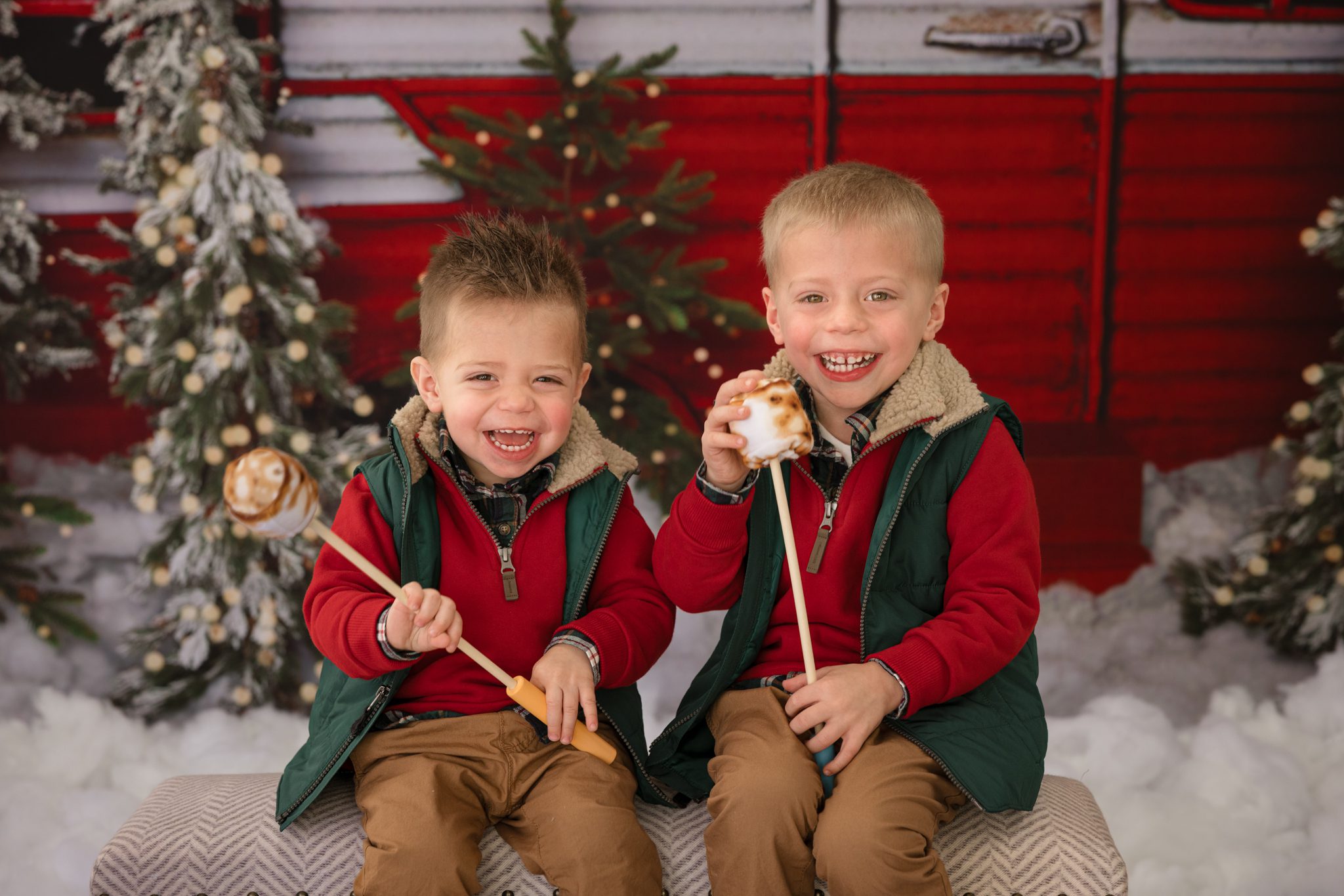 Two young boys sitting in front of a Christmas camper laughing hysterically