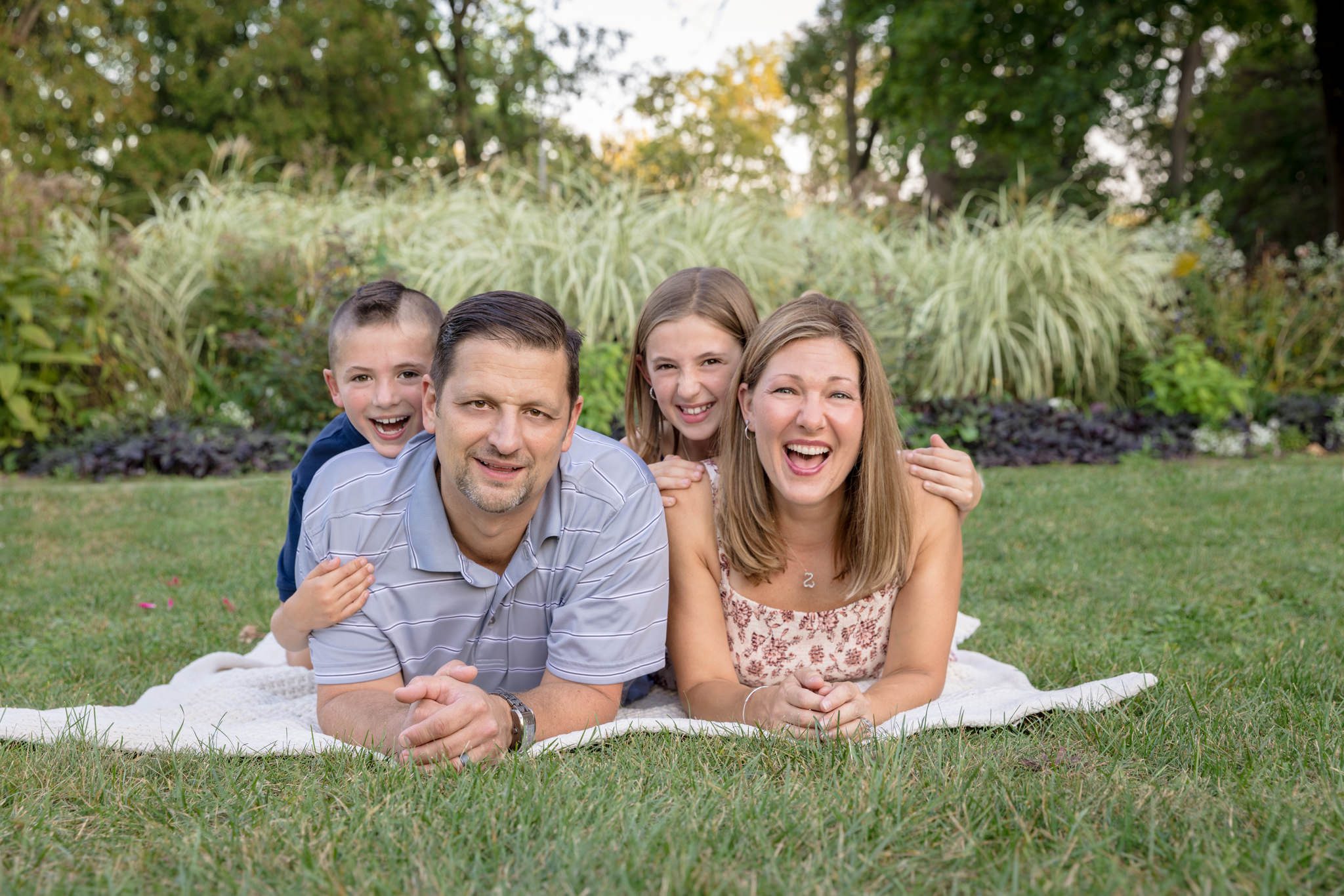family of four lying on their bellies and smiling at the camera. Taken at Fabyan Park in Geneva, IL